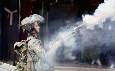 An Israeli policeman fires tear gas during clashes with Palestinian demonstrators, in the West Bank town of al-Ram, north of Jerusalem.