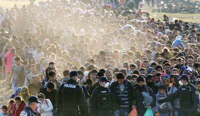 Migrants and refugees are escorted by Slovenian soldiers and police officers as they walk towards a refugee camp after crossing the Croatian-Slovenian border near Rigonce, Slovenia.