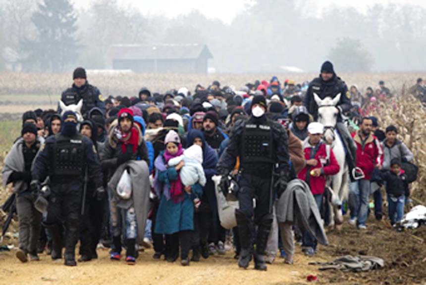 Escorted by police, migrants move through fields after crossing from Croatia, in Rigonce, Slovenia on Tuesday.