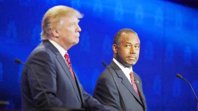 Ben Carson, right, watches Donald Trump during the CNBC Republican presidential debate at the University of Colorado in Boulder, Colo on Wednesday