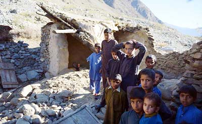 Afghan earthquake survivors gather in their damaged house, in Kesu village, some 15 km from Chitral on Wednesday.