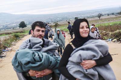 Migrants and asylum seekers carry their children as they walk on a dirt road after crossing the Macedonian-Serbian border near the village of Miratovac.