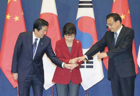 South Korean President Park Geun-hye, centre, shakes hands with Japanese Prime Minister Shinzo Abe, left, and Chinese Premier Li Keqiang as they meet to hold a trilateral summit at the presidential house in Seoul, South Korea on Sunday.