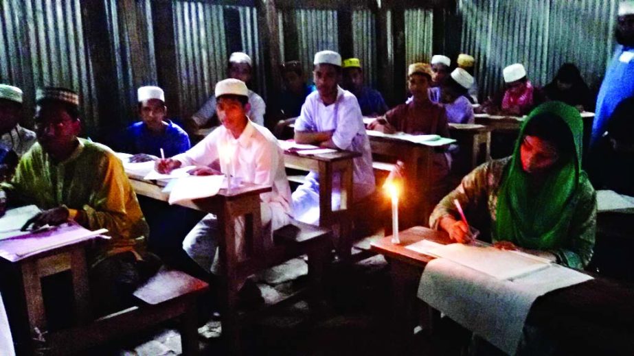 BETAGI (Barguna): JSC students at Betagi Chhalayhia Senior Madrasa Centre in Betagi Pourashva using candle light for lack of electricity during the first of day the examination on Sunday.