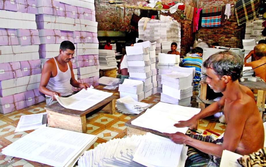 Workers of various bookbinders in city are busy to complete the task for distribution of books to students in New Year as directed by the Govt. This photo was taken from city's KM Dash Lane on Friday.