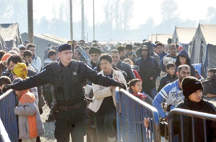 A Croatian policeman stands guard as migrants and refugees queue to enter a transit camp in Slavonski Brod.