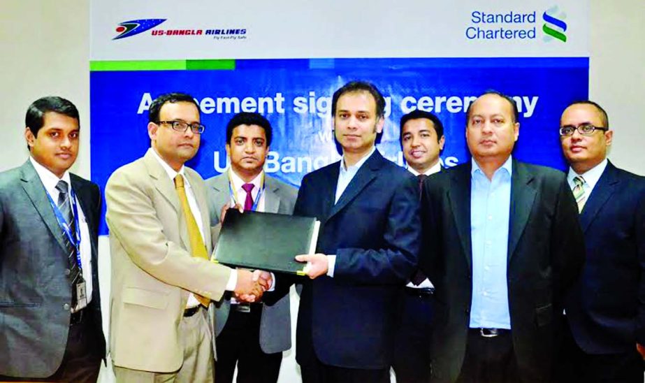 Shafiqul Islam, Head of Sales and Marketing of US-Bangla Airlines and Md Mahiul Islam, Head of Brand and Marketing of Standard Chartered Bank exchanging the deal at the bank's head office in the city recently.