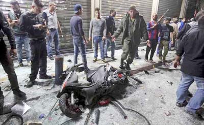 A motorcycle is seen amid residents inspecting a damaged area caused by two explosions in Beirut's southern suburbs, Lebanon on Thursday.