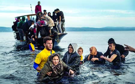 Greek lifeguards help refugees and migrants to disembark from a small boat after their arrival from the Turkish coast on the northeastern Greek island of Lesbos. Internet photo