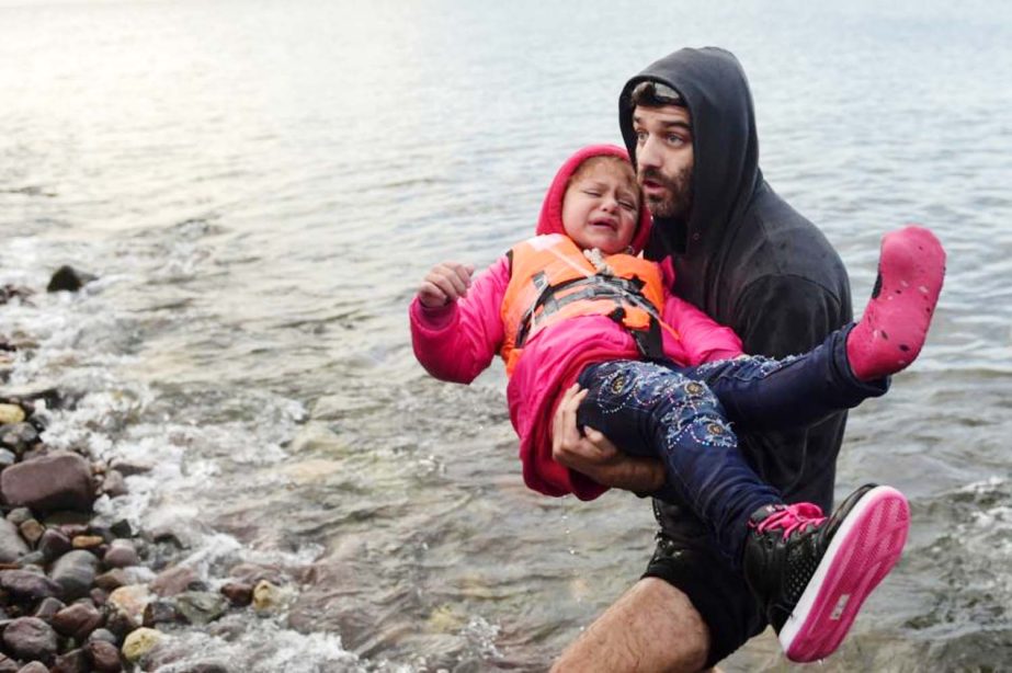 A migrant carries a girl upon their arrival on the Greek island of Lesbos after crossing the Aegean Sea from Turkey with others on Tuesday.