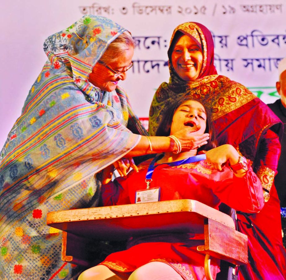 Prime Minister Sheikh Hasina coddles a disabled child at a ceremony for handing over national identity cards among the disabled at Bangabandhu International Conference Center in the city on Thursday marking National Day for Disabled. BSS photo