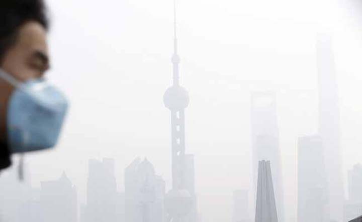 A man wearing a face mask walks on a bridge in front of the financial district of Pudong amid heavy smog in Shanghai, China, on Tuesday.