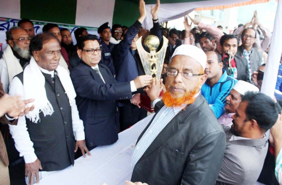 Justice of High Court Division of Supreme Court Md Faruque handing over the championship trophy of Harunur Rashid, MP Memorial Gold Cup Football Tournament to Muradnagar Sub-Registry Office Deed Writersâ€™ Association team at DR Government High Schoo