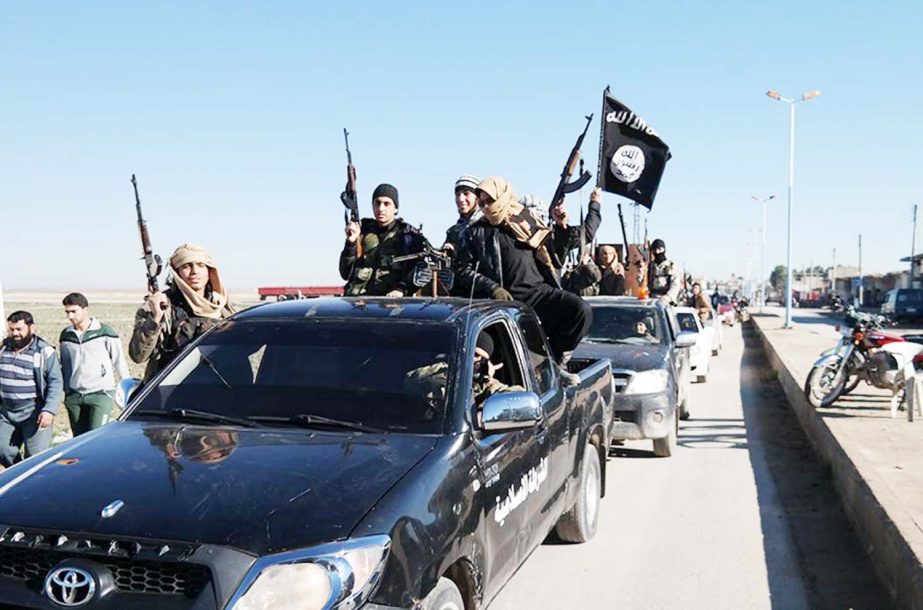 Islamic State militants pass by a convoy in Tel Abyad town, northeast Syria.