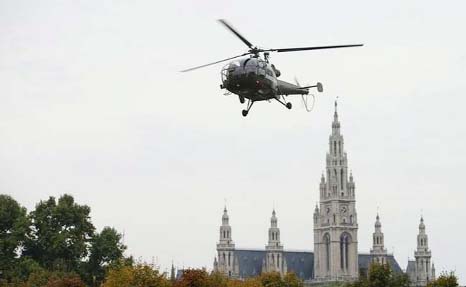 An Austrian Army Alouette III helicopter hovers in front of the city hall in Vienna, Austria.