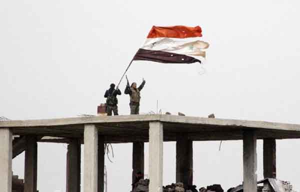 Syrian government forces wave the national flag in Deir al-Adas in the Daraa province.