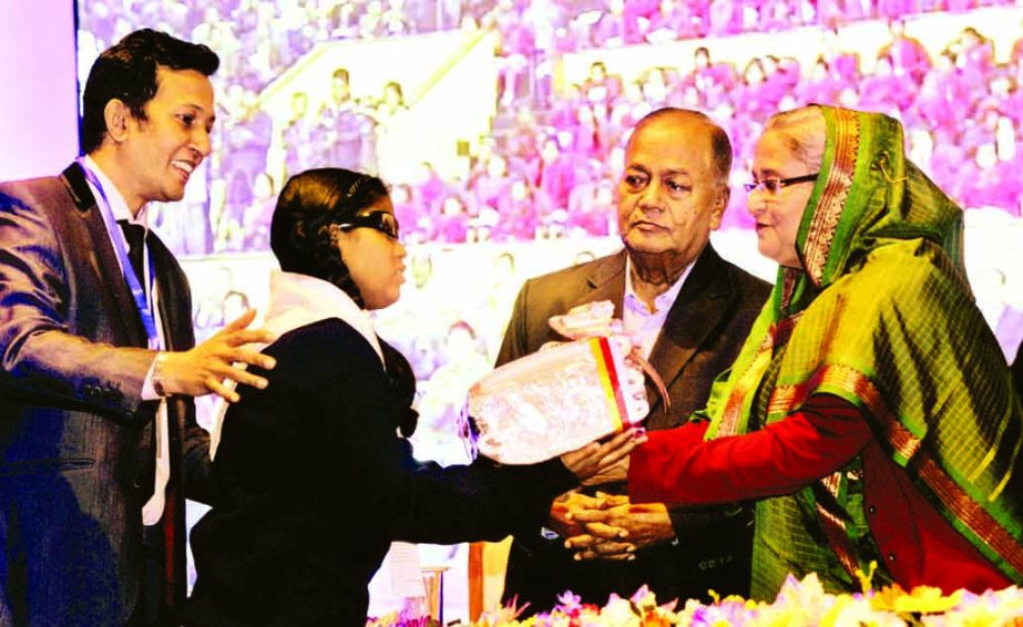 Prime Minister Sheikh Hasina handing over braille system textbooks among the visually impaired students in Osmani Memorial Auditorium in the city on Saturday marking Social Services Week-2016. BSS photo