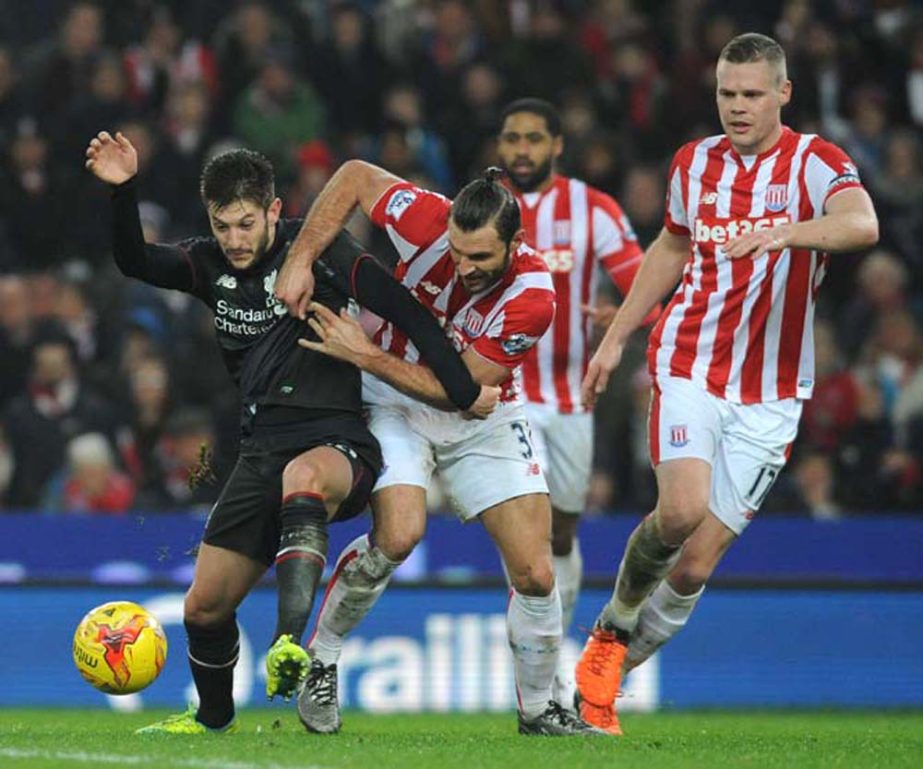 Liverpoolâ€™s Adam Lallana, left, is held back by Stoke Cityâ€™s Erik Pieters, centre, watched by Stokeâ€™s Ryan Shawcross, right, during the first leg of the English League Cup semifinal soccer match between Stoke City and Liverpool at the