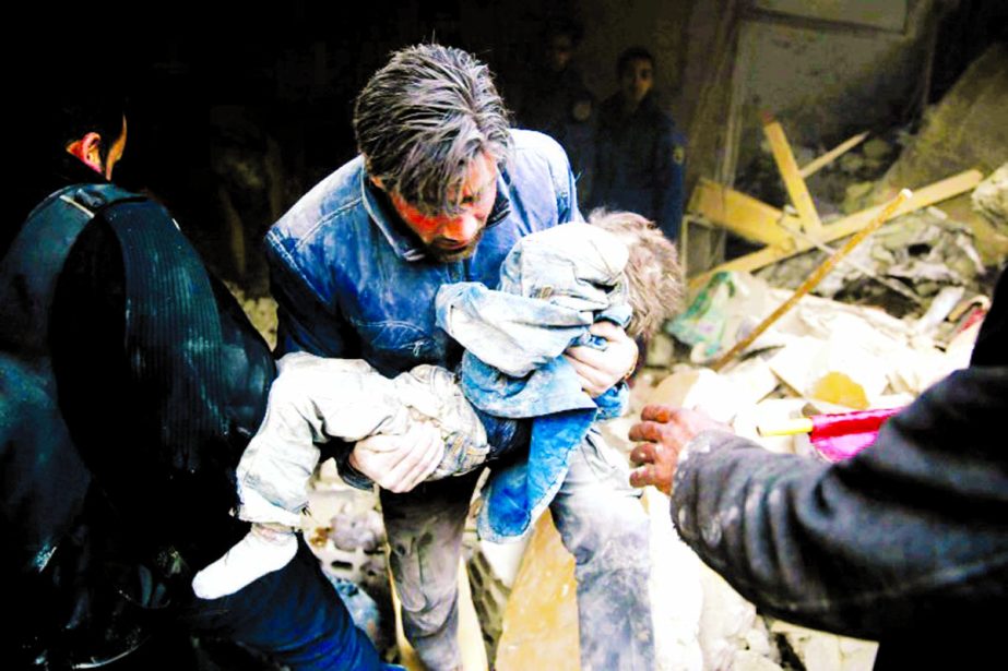 A Syrian man evacuates a child from the rubble of a destroyed building following air strikes on the Eastern Ghouta town of Douma.