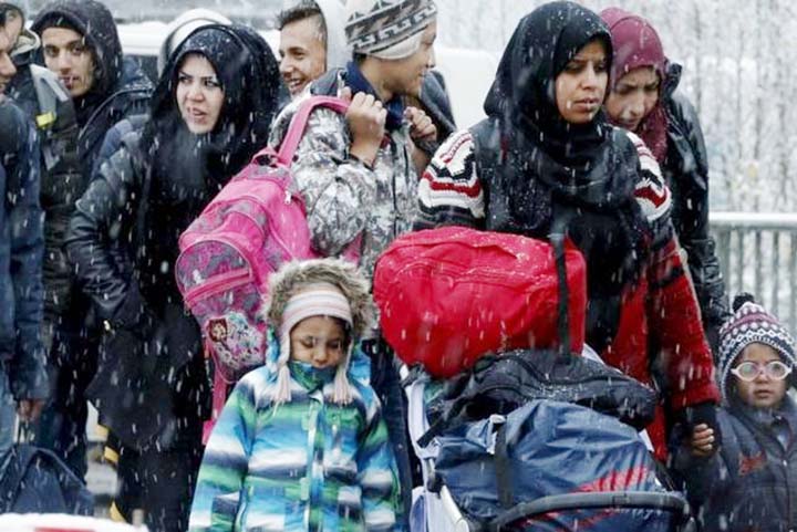 Migrants stand in queue during snowfall before passing Austrian-German border in Wegscheid in Austria, near Passau.