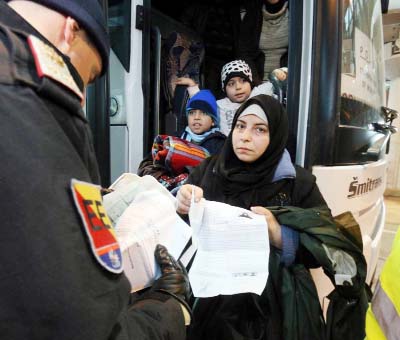 An Austrian police officer checks the identification documents of migrants before allowing them to get out a bus from Slovenia to cross the border from Slovenia into Austria, at a checkpoint at the Karawanks tunnel near Villach, Austria on Wednesday.