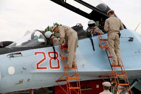 Russian servicemen assist air force pilots in a Sukhoi Su-30SM fighter jet before departure on a mission at the Hmeimim military base in Latakia province, in the northwest of Syria.