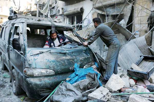 Syrian men inspect a damaged vehicle in the rubble following a reported air strike by Syrian government forces on the Sukkari neighbourhood of Syria's northern city of Aleppo on Monday.