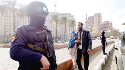 A woman walks past an Egyptian policeman, on the eve of the fifth anniversary of the 2011, uprising in Tahrir Square, Cairo