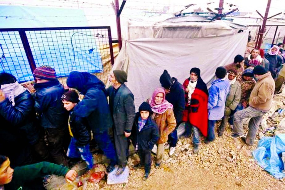 Internally displaced Syrians queue to receive blankets near the Bab al-Salam crossing, across from Turkey's Kilis province, on the outskirts of the northern border town of Azaz, Syria on Sunday.