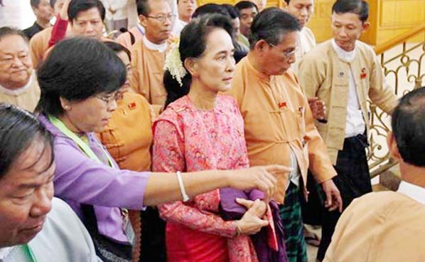 Myanmar's pro-democracy leader Aung San Suu Kyi, center, arrives to participate in the inaugural session of Myanmar's lower house parliament on Monday.