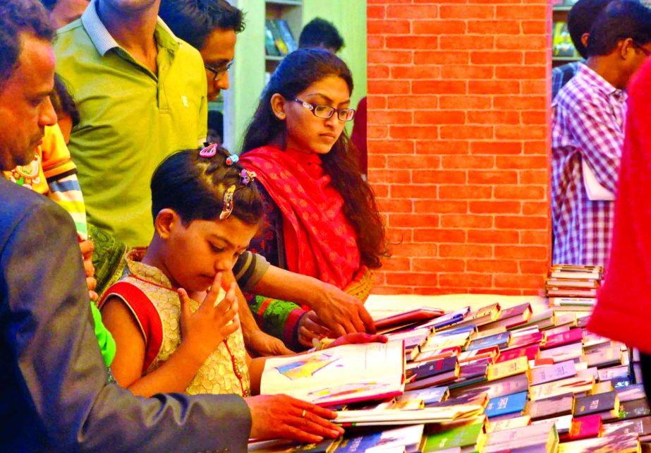 Parents helping their child to choose books at Ekushey Boi Mela on Monday