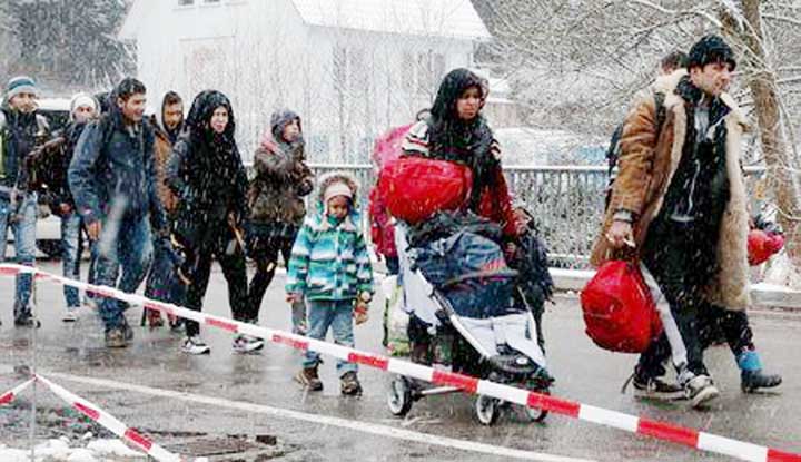 Migrants stay in queue during heavy snowfall before passing Austrian-German border in Wegscheid in Austria, near Passau.