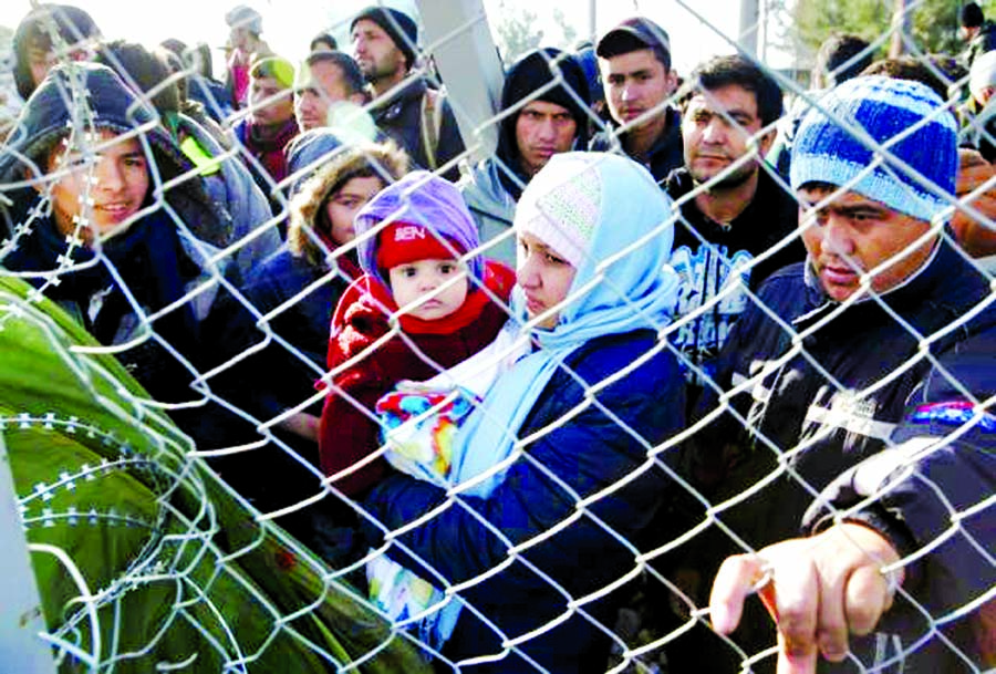 Migrants stand next to a border fence at the Greek-Macedonian border, after additional passage restrictions imposed by Macedonian authorities left hundreds of them stranded near the village of Idomeni, Greece, February 23, 2016. Internet photo