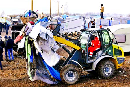 A bulldozer clears away tents and debris while migrants who once lived in the camp watch on Internet photo