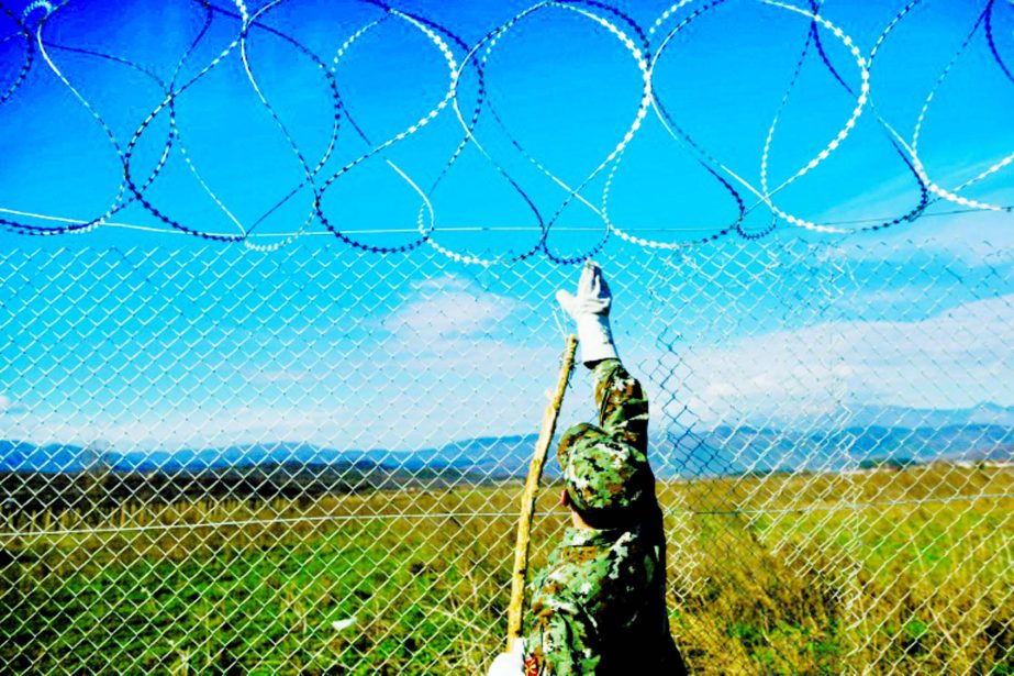 A Macedonian soldier fixes a barbed wire fence to prevent illegal crossings by migrants at the border between Greece and Macedonia near Gevgelija.