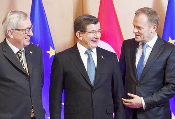 Turkish Prime Minister Ahmet Davutoglu is welcomed by European Commission President Jean-Claude Juncker (L) and European Council President Donald Tusk (R) during an EU-Turkey summit in Brussels on Monday.