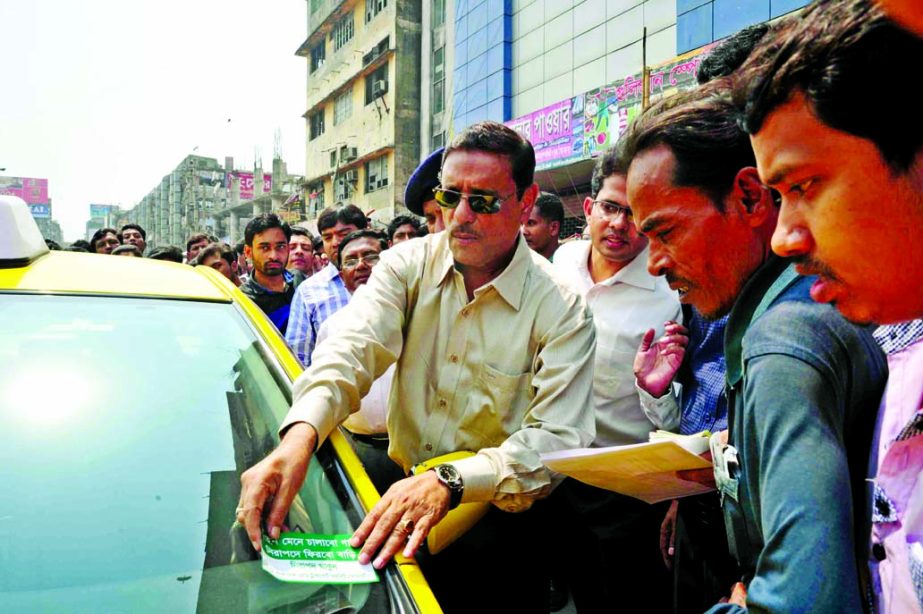 Road Transport and Bridges Minister Obadul Quader pasting sticker on a taxi-cab during distribution of leaflets to raise awareness among the drivers and pedestrians. The snap was taken from the city's Gulistan area on Tuesday.