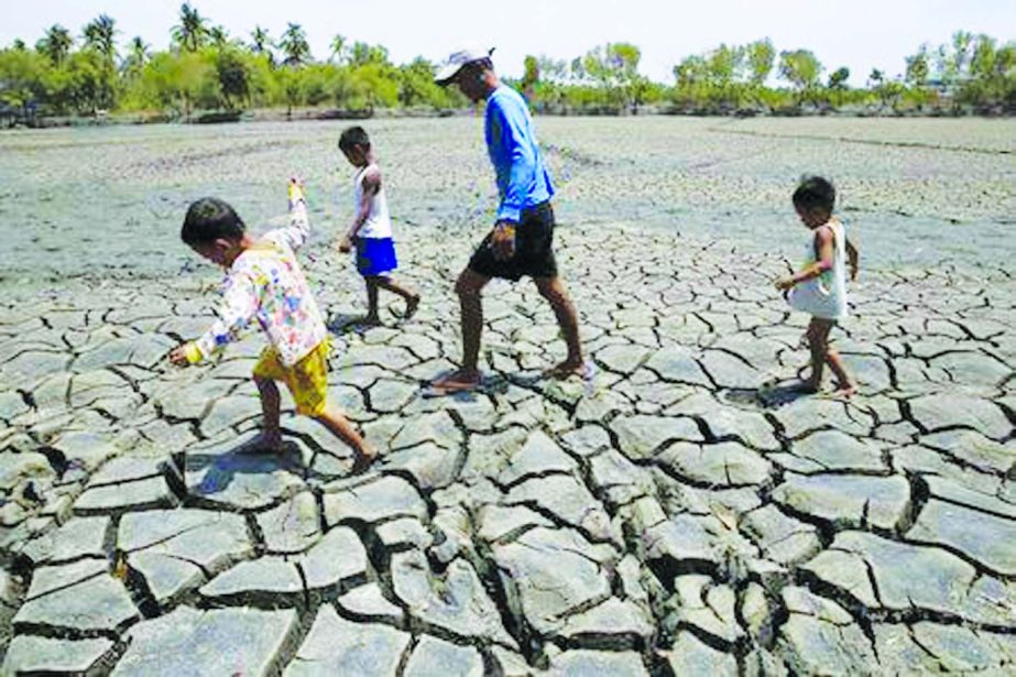 A father with his children walk over the cracked soil of a 1.5 hectare dried up fishery at the Novaleta town in Cavite province, south of Manila .