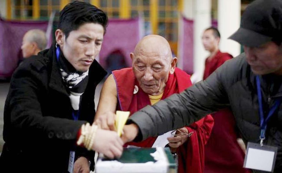 Polling officers help a Tibetan monk to cast his vote during the election for the Tibetan government-in-exile at a polling booth in Dharamsala on Sunday.