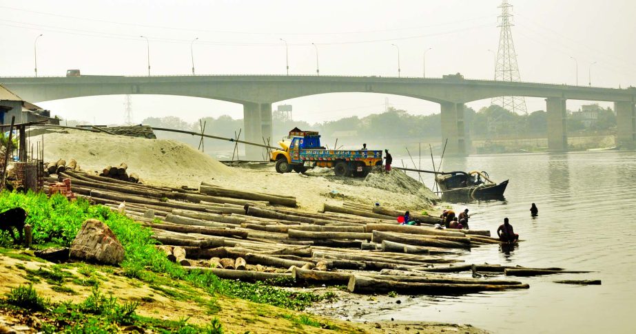 Illegal sand and wood-log businesses thriving beneath the Sultana Kamal Bridge in Tarabo area despite High Court's embargo. This photo was taken on Monday.