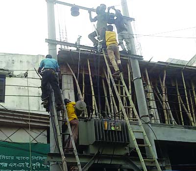 SIRAJGANJ: Employees of electricity department repairing transformer standing on the high voltage wire without taking accurate safety measures . This picture was taken from SS Road in Sadar Upazila on Wednesday.