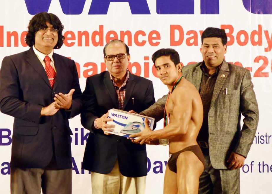 State Minister for Youth and Sports Biren Sikder, MP handing over the prize to a winner of the Walton Independence Day Bodybuilding Competition at the Auditorium of the National Sports Council Tower on Tuesday.