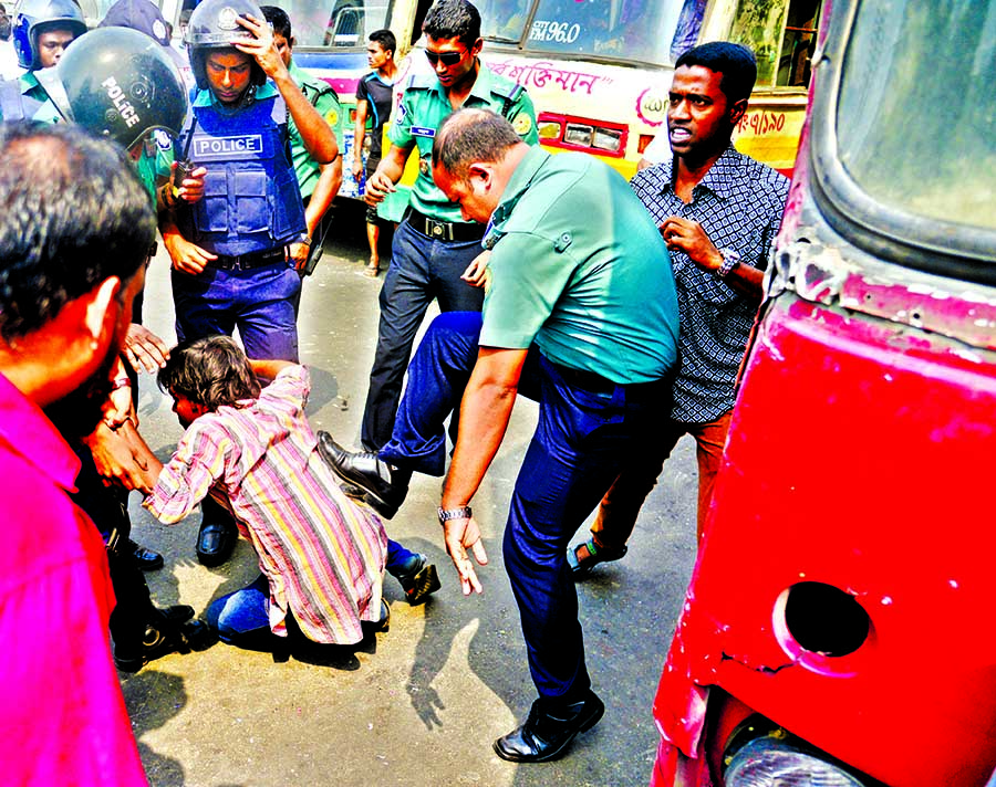 Police kick a protester at Shahbagh Intersection during the demonstration by the students demanding punishment to Tonuâ€™s killers.