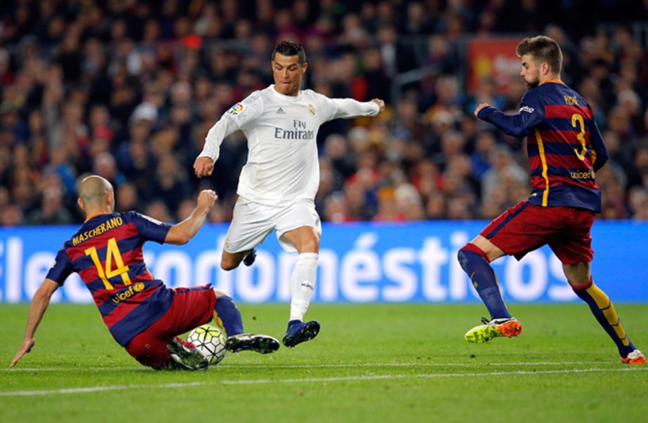 Real Madrid's Cristiano Ronaldo (center) attempts a shot at goal between Barcelona's Javier Mascherano (left) and Gerard Pique during a Spanish La Liga soccer match between Barcelona and Real Madrid, dubbed 'el clasico', at the Camp Nou stadium in Bar