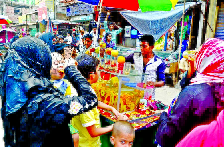 The people including women and children taking juice from a way-side makeshift stall to get relief from Saturday's blistering heat at Siddik bazar area in city.