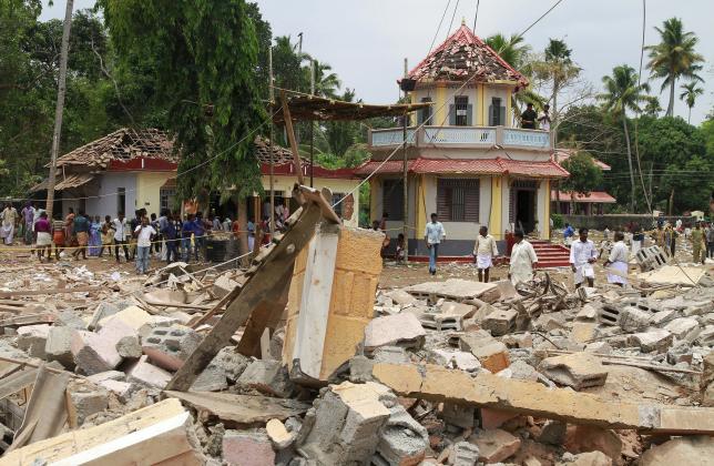 People stand next to debris after a broke out at a temple in Kollam in the southern state of Kerala, India, April 10, 2016. ReutersSivaram V