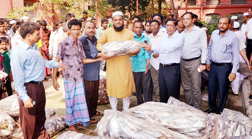 Deputy Commissioner of Chittagong Mezbah Uddin distributing 'Jatka' fish among the head of different orphanages that was recovered from Fishery Ghat by the law enforcers on Monday.