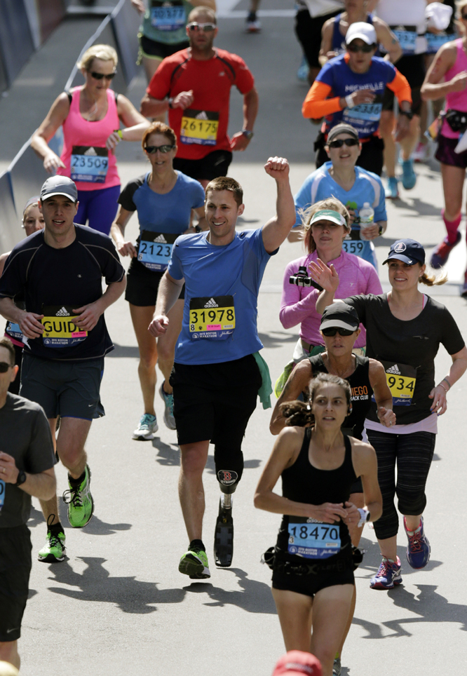 Boston Marathon bombing survivor Patrick Downes raises his fist as he approaches the finish line of the 120th Boston Marathon in Boston on Monday.