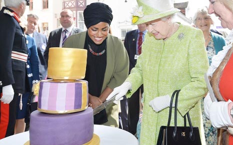 Britain's Queen Elizabeth cuts the cake Nadiya Hussain, winner of the Great British Bake Off baked for her, as she walks through Windsor on her 90th Birthday, in Windsor, Britain on Thursday.