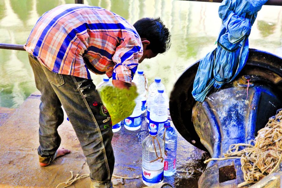 A group of syndicate engaged in impure water business in city as heat wave have been continuing across the country. Photo shows a boy is seen bottling WASA pump water on Friday which are being sold to the commuters as pure drinking water.